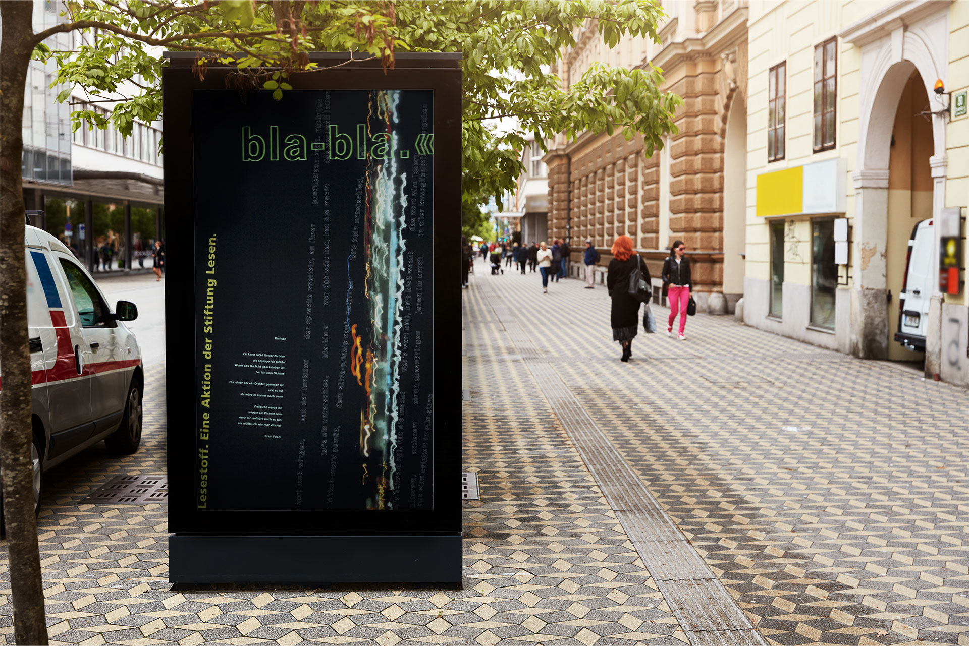 pedestrian zone with a billboard arranged on the left side of the image and a poster with light movements on it. in the background there is a woman dressed in black with red hair.